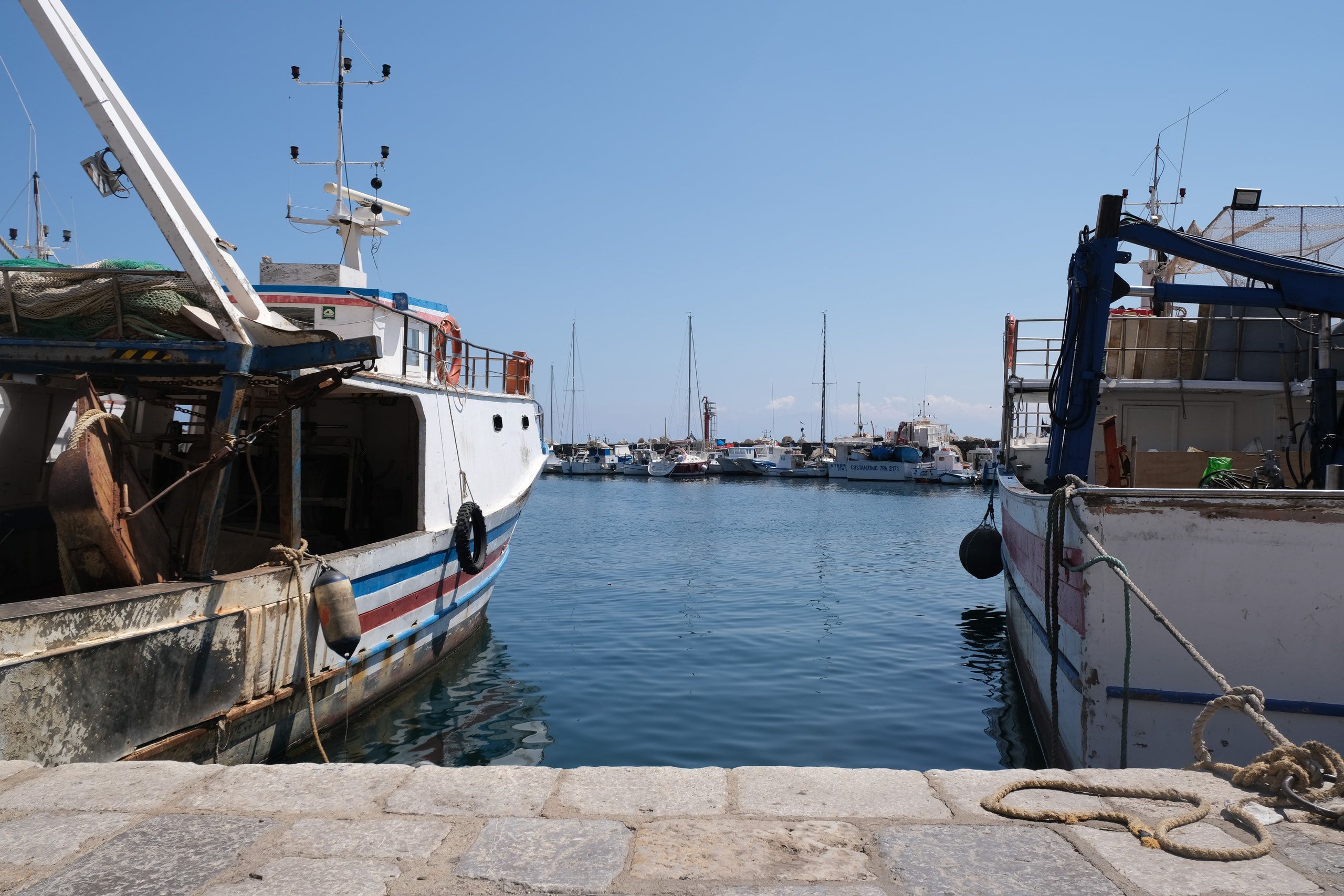 Il porto di Porticello visto fra due pescherecci ormeggiati, con altre barche sullo sfondo