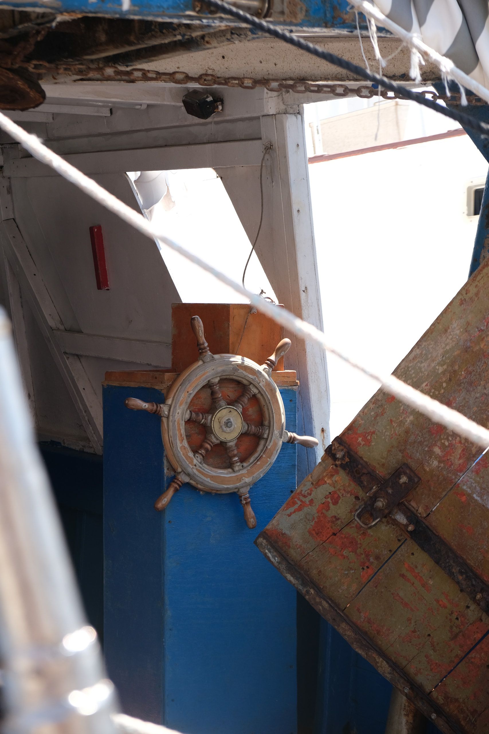 La plancia di una barca da pesca, con il timone a ruota e una cassetta di legno