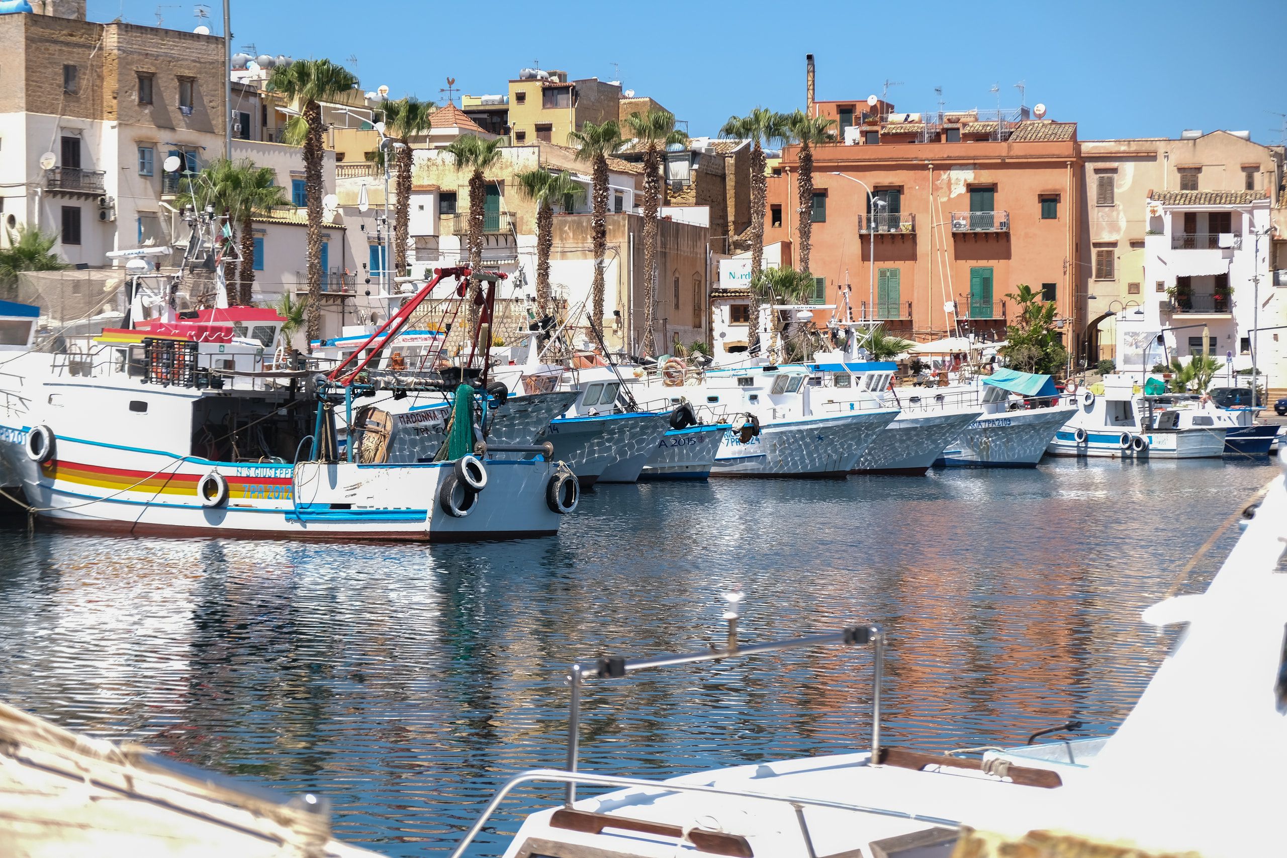 Le barche ormeggiate nel porto di Porticello, davanti alle case e alle palme