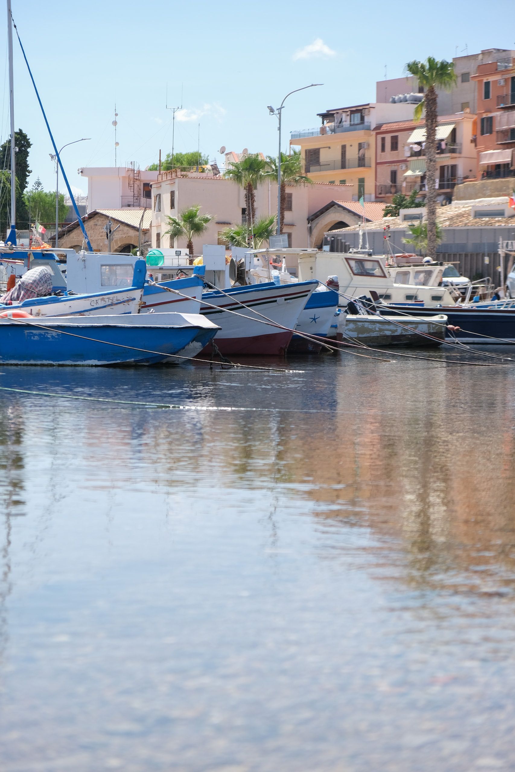 L'acqua bassa e trasparente in primo piano e, più in là, barche ormeggiate e case con le palme