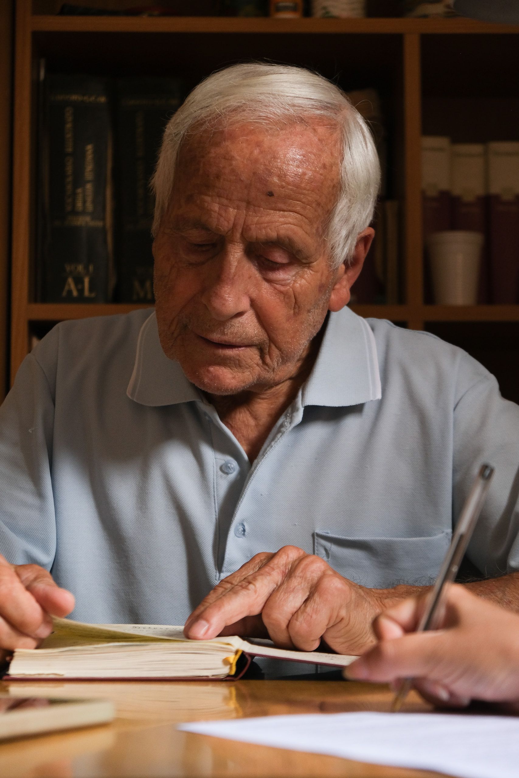 Filippo Castro, a capo chino, legge un libro aperto sul tavolo dello studio