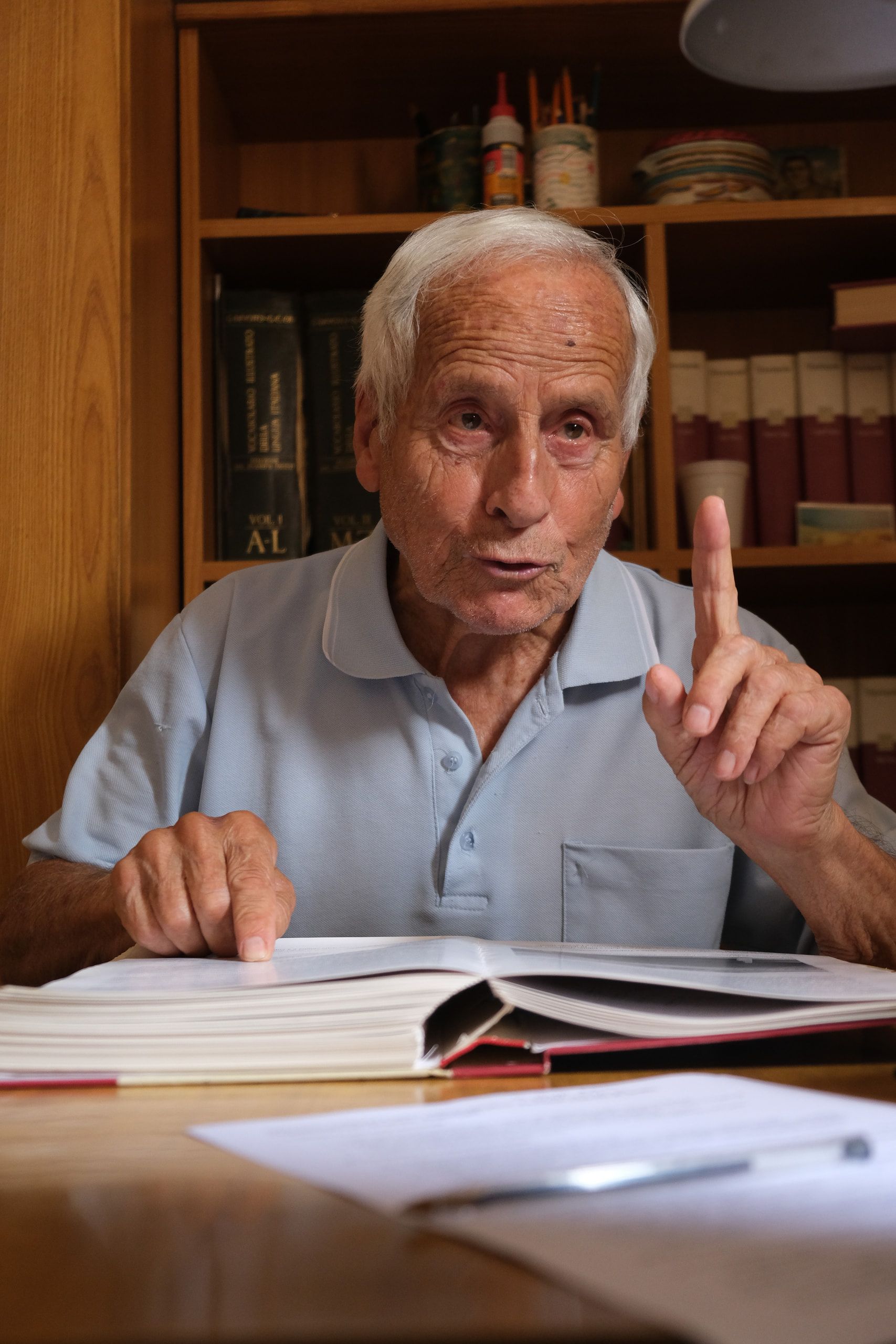 Filippo Castro alza l'indice mentre parla, con l'altra mano su un grande album aperto
