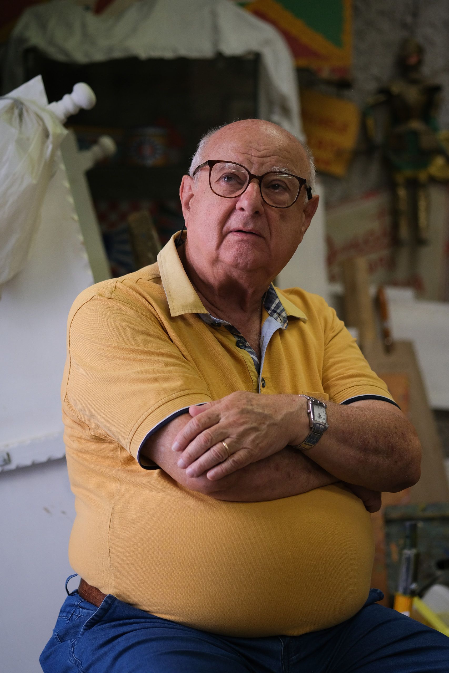 Un ospite anziano della bottega ascolta seduto, con le braccia incrociate