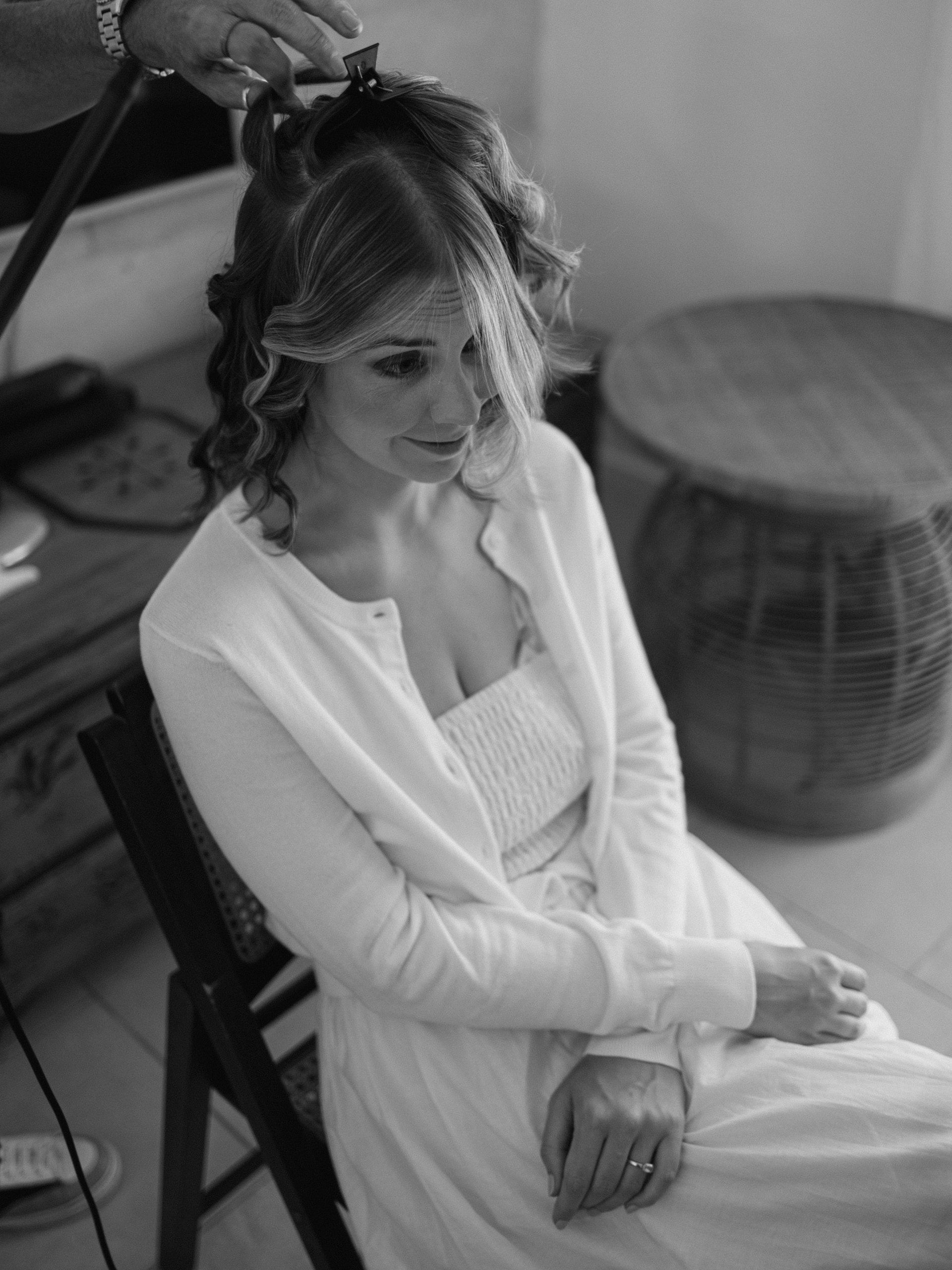 In bianco e nero, la sposa seduta mentre qualcuno le acconcia i capelli