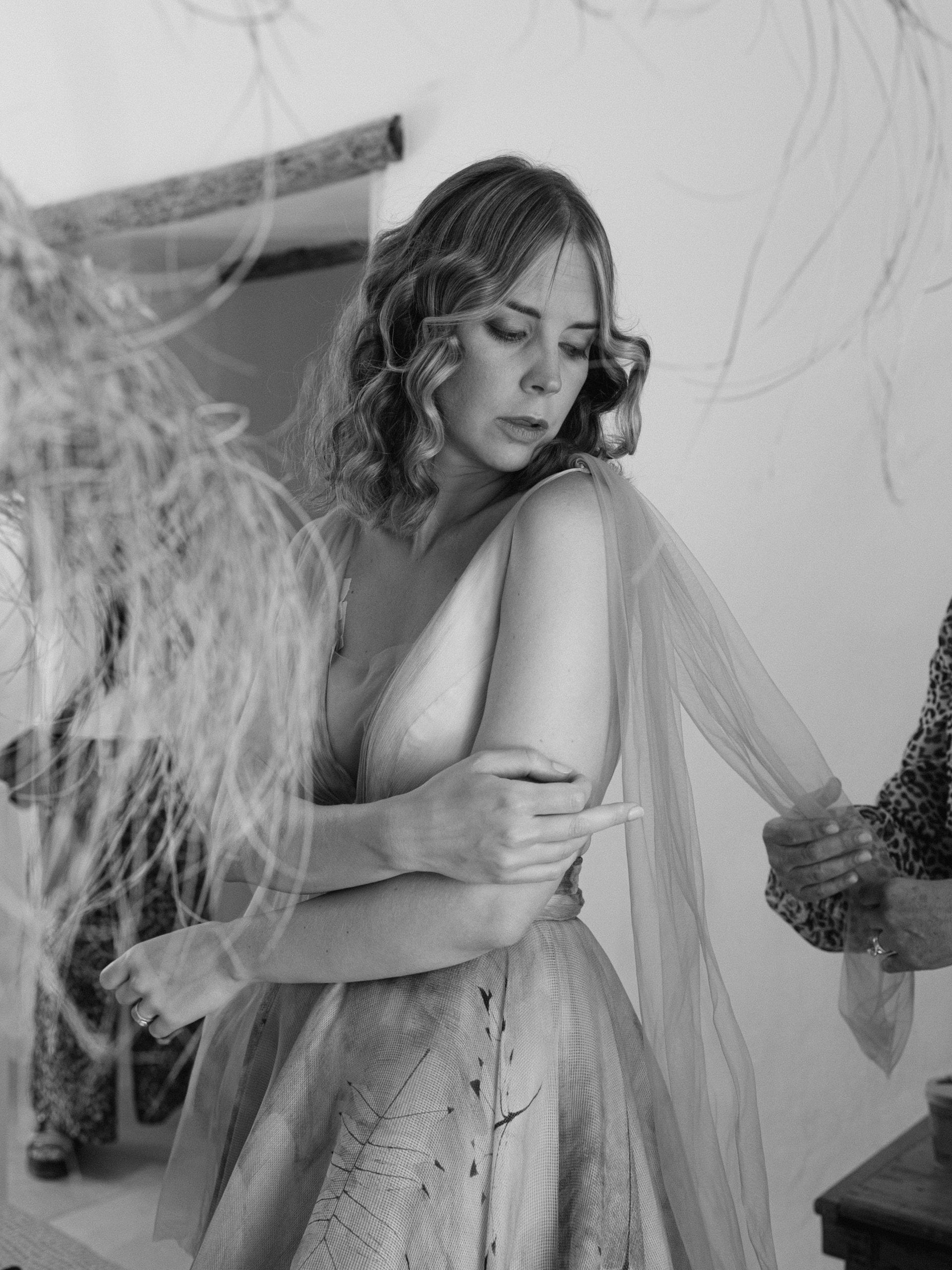 In bianco e nero, la sposa si sistema una manica di tulle del vestito