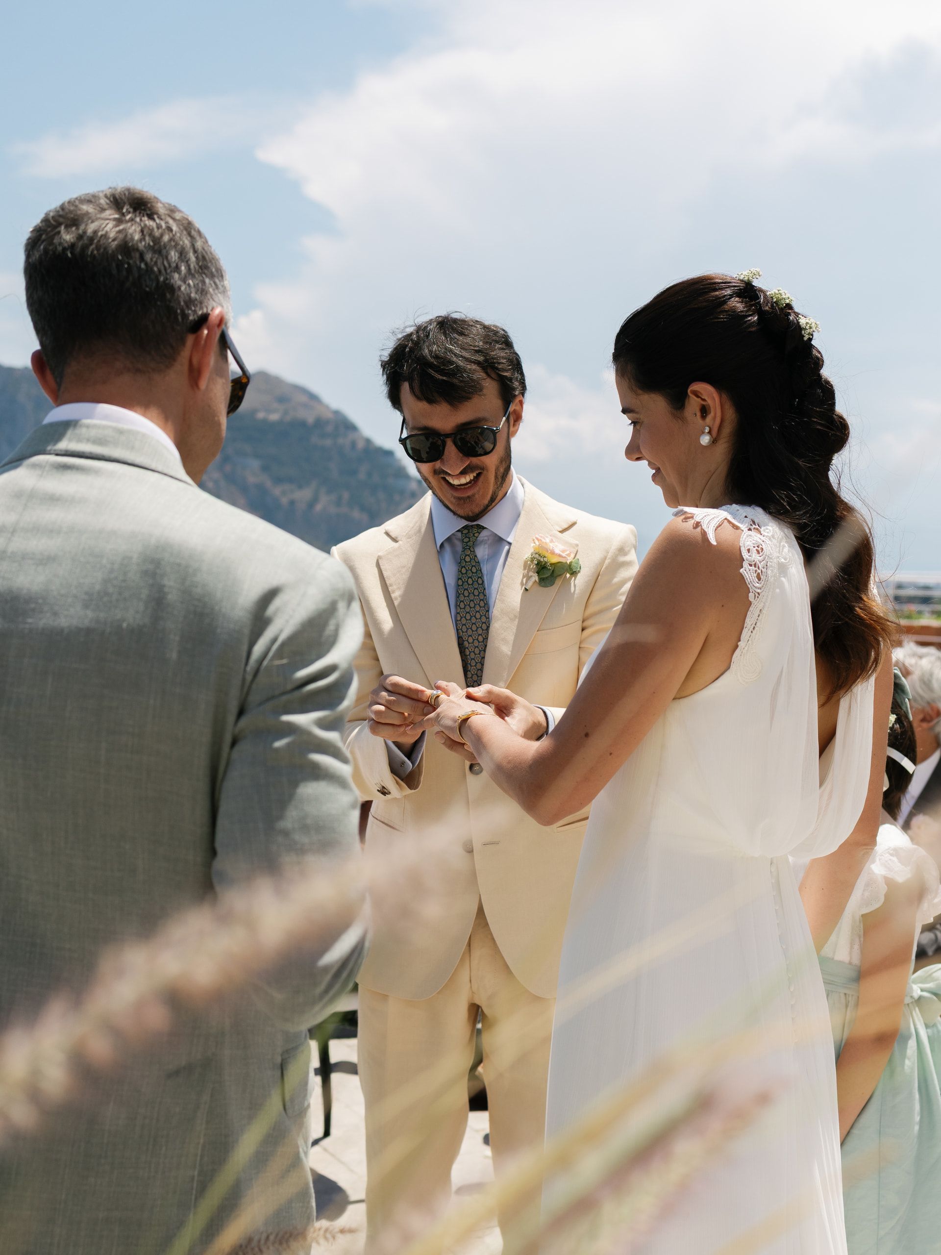 Lo sposo infila l'anello alla sposa davanti al celebrante, ripreso di spalle